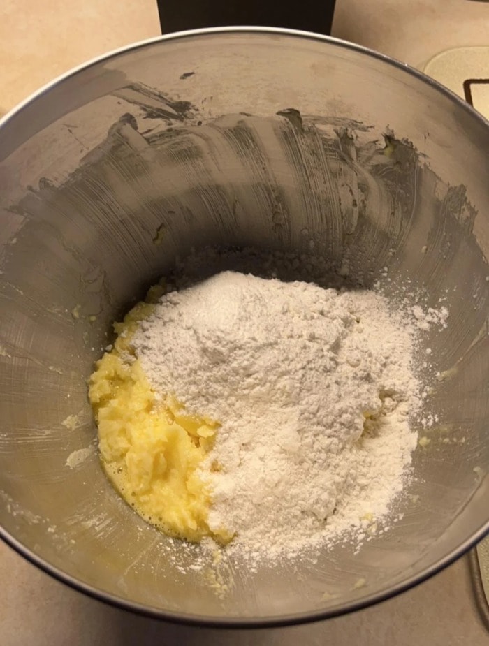 adding flour to the cookie dough in the mixing bowl