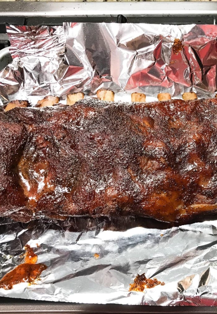 a rack of baby back pork ribs that got smoked at 225°F for 7 hours on a sheet of aluminnum foil