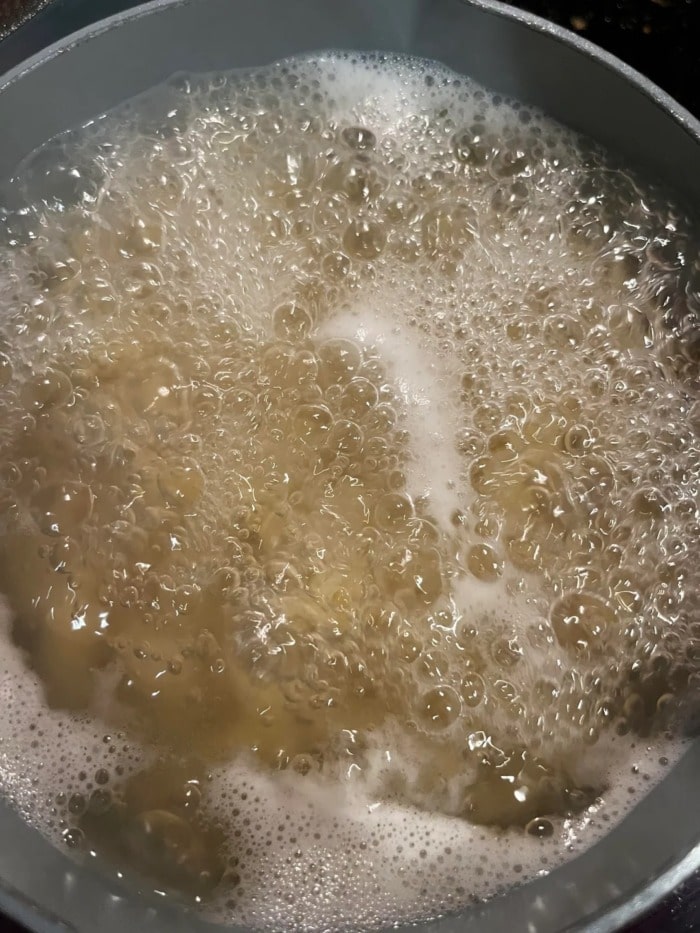a close up of boiling noodle water showing the liquid's surface agitation