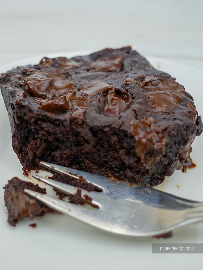 a close up of a fudgy brownie made without eggs and sliced with a fork with its inside visible