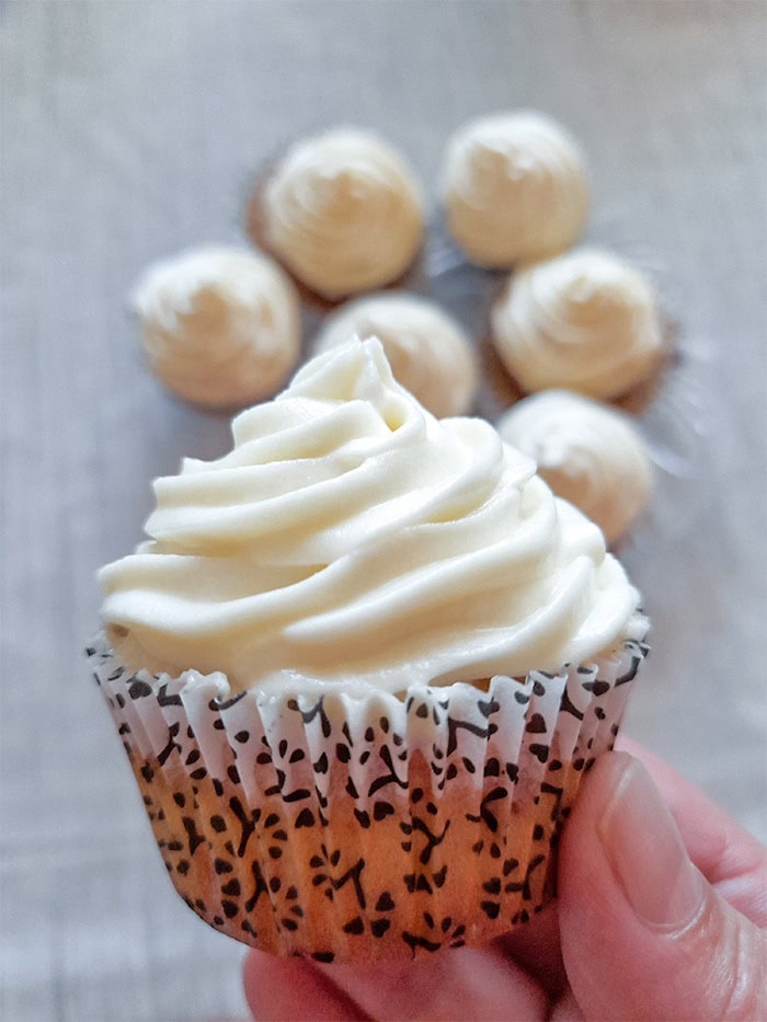 a close up of an egg free  vanilla cupcake with fluffy vanilla frosting