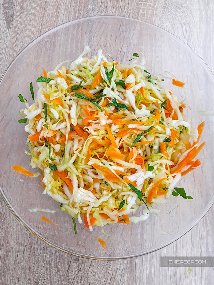 cabbage carrot salad in a glass bowl on a wooden table