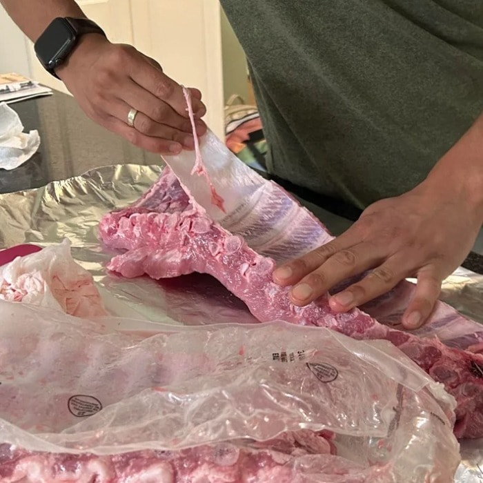 A person removing the membrane from pokr spare ribs using their fingers