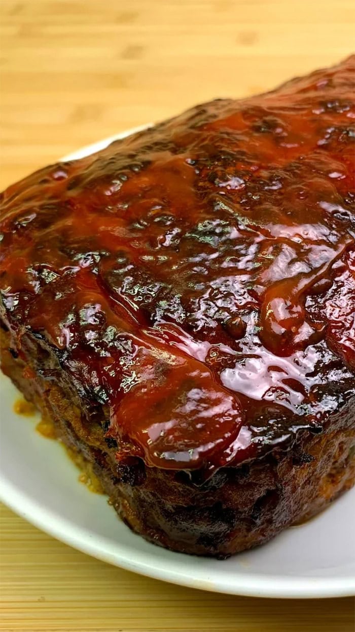 Classic homemade meatloaf with a thick caramelized glaze served whole on a white plate.