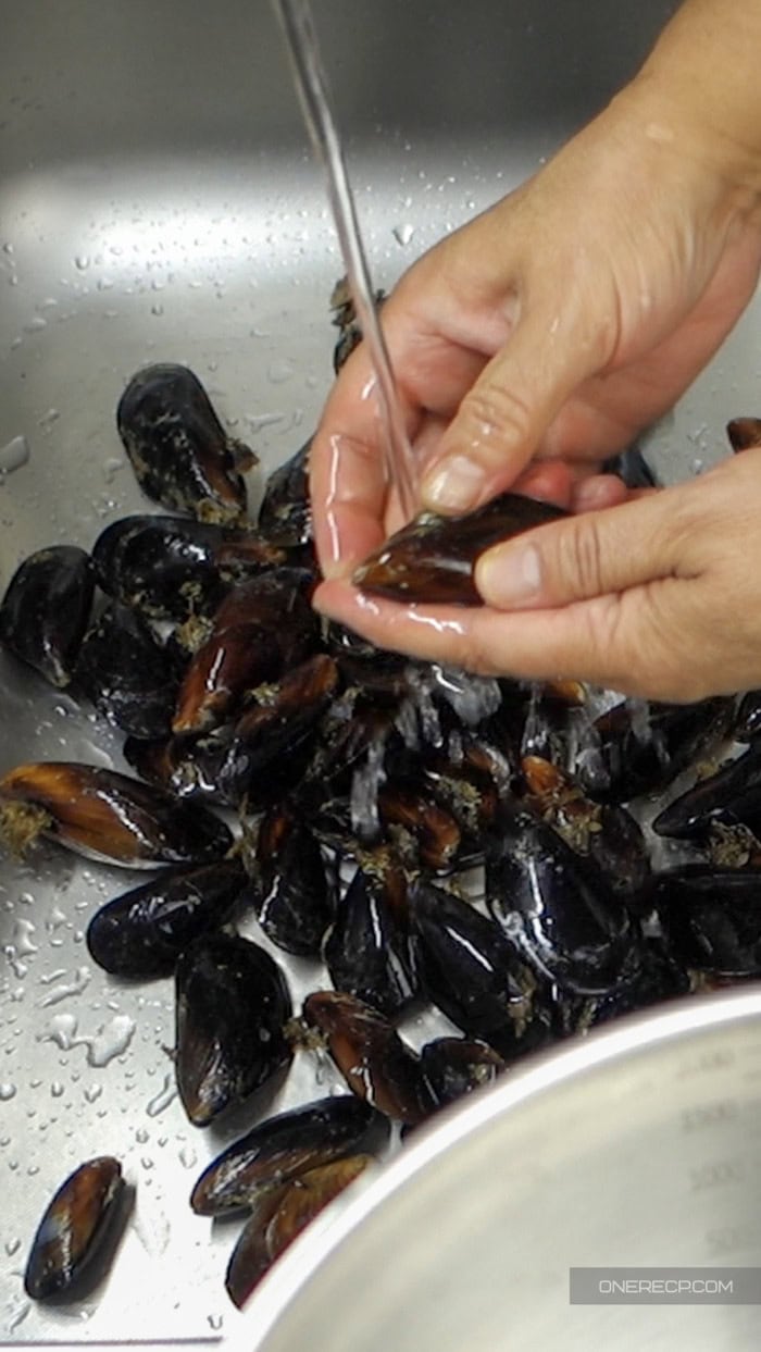 Cleaning a mussel by hand under cold running water