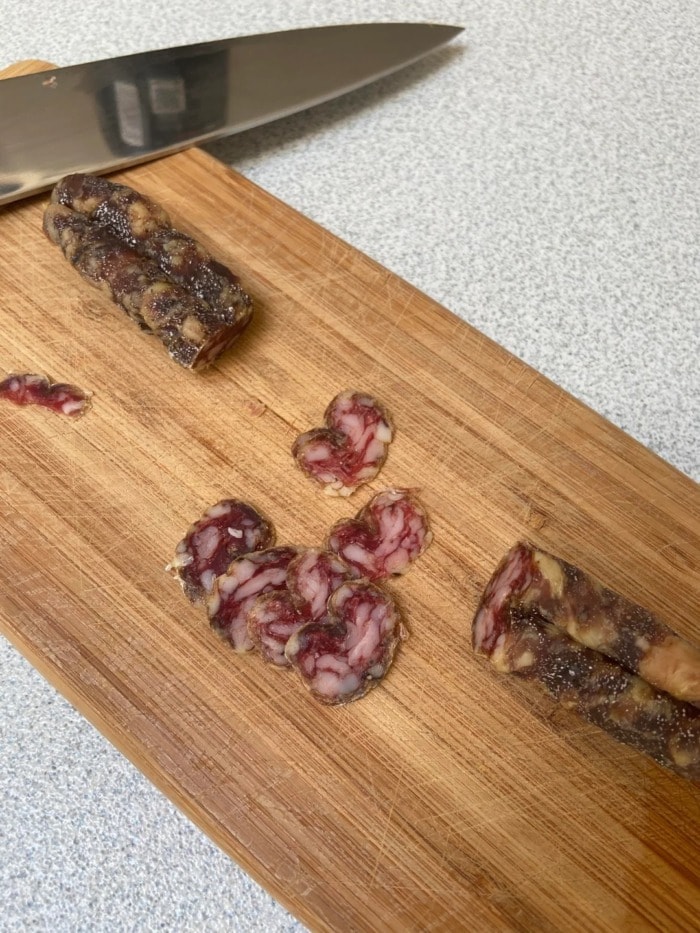 cured sausage with white spots cut on wooden board 