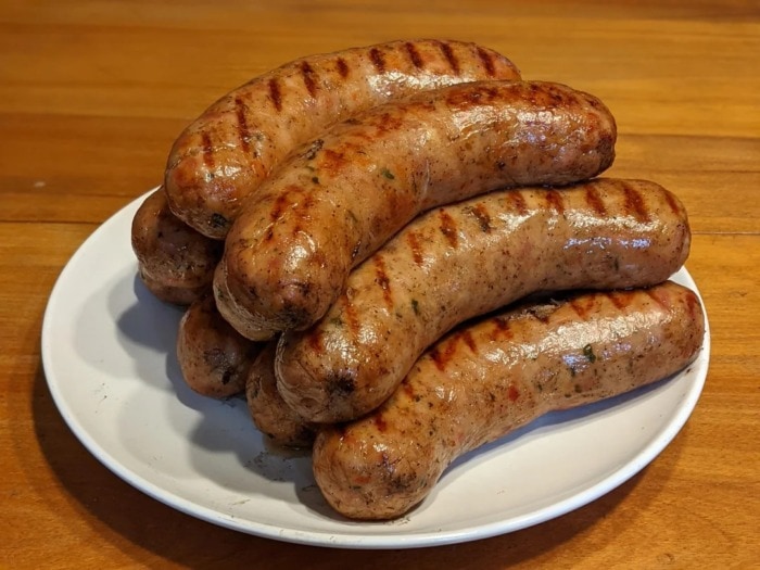 a plate with cooked sausages with natural casing where the rounded edges of each sausage are visible