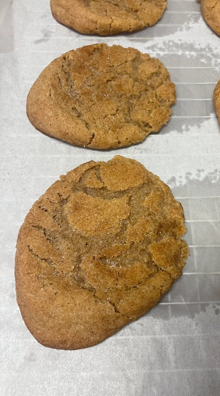 Flat, uneven cookies on a baking sheet, showing how old flour can affect texture.
