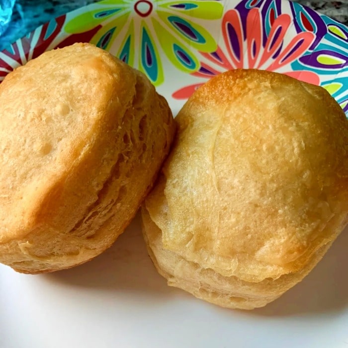 two puffy baked canned biscuits on a colorful plate