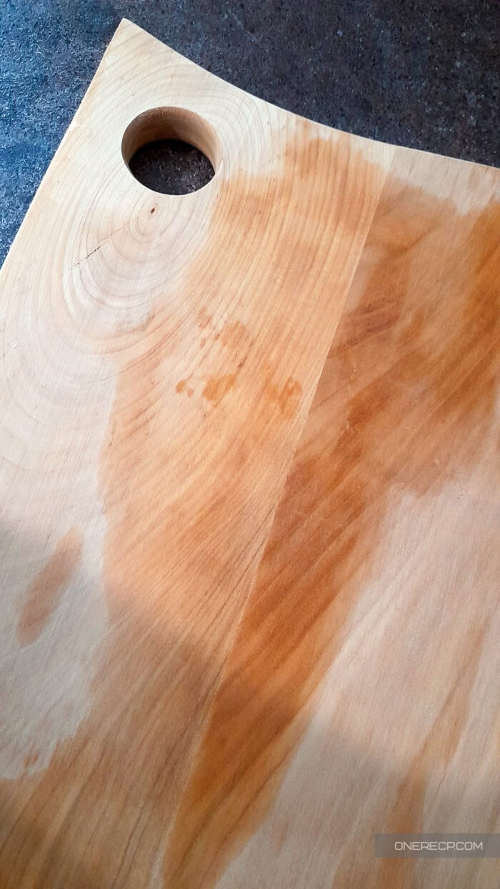 A freshly cleaned wooden cutting board drying upright with visible moisture marks.
