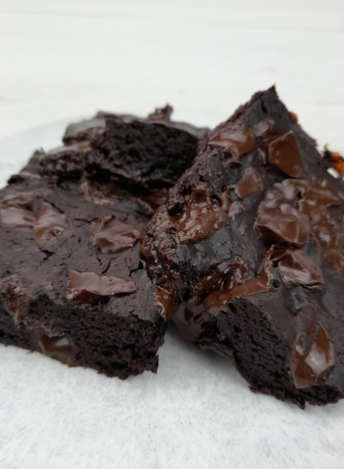 close up of 2 eggless brownies with chocolate chunk and cocoa powder