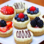 a plate of mini eggless cheese cakes with fruit decorations