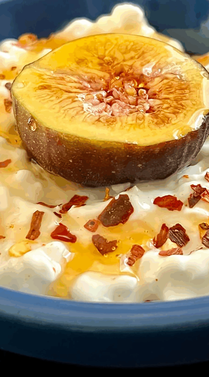 A fresh fig half drizzled with honey resting on creamy yogurt and sprinkled with chili flakes for a naturally sweet and spicy dessert idea.