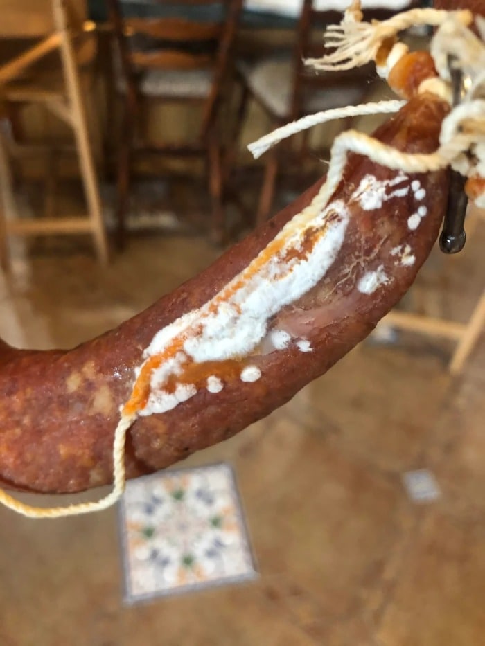cured sausage covered with inedible bad fluffy white mold