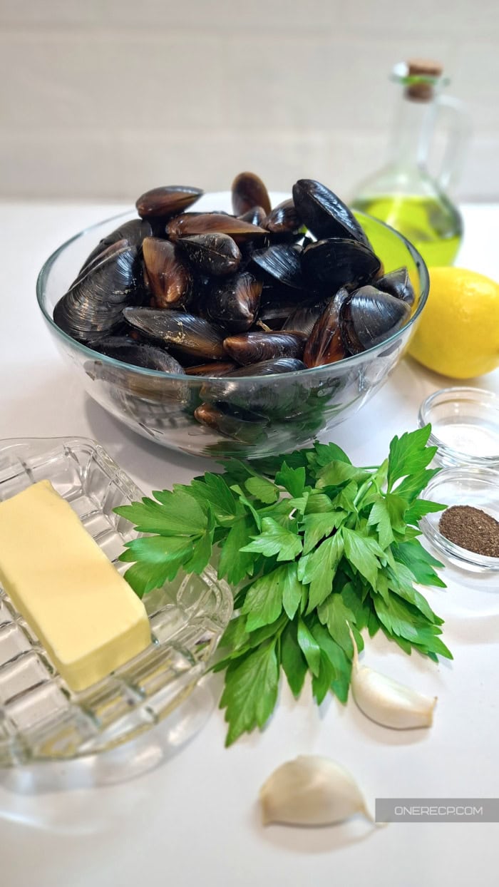 Fresh mussels with garlic, butter, parsley, lemon and olive oil ingredients on a countertop