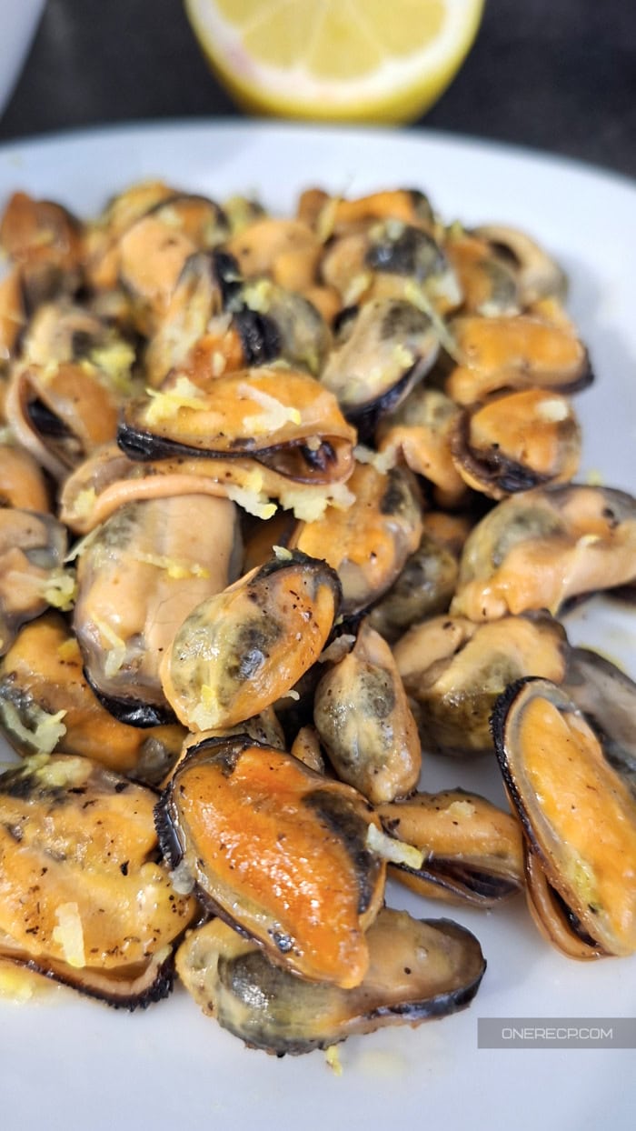 Fried mussels recipe with garlic and lemon zest served on a plate
