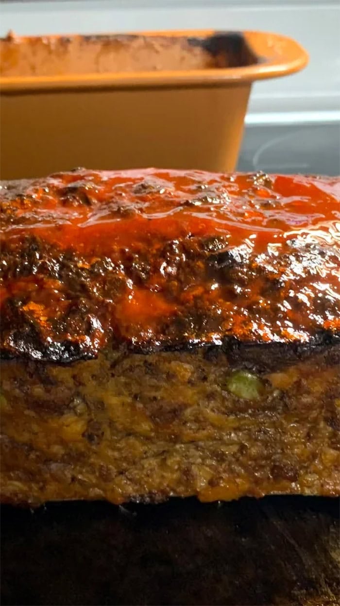 Freshly baked meatloaf with a glossy ketchup glaze resting in a silicone loaf pan after baking.