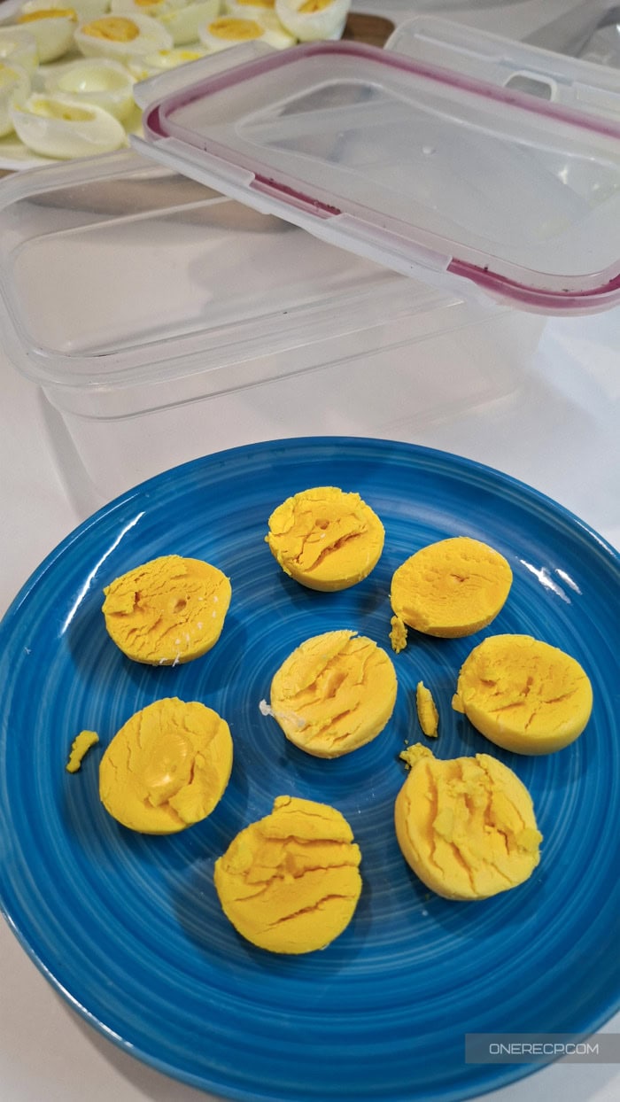 Cooked egg yolk halves separated from the whites and arranged on a blue plate before freezing.
