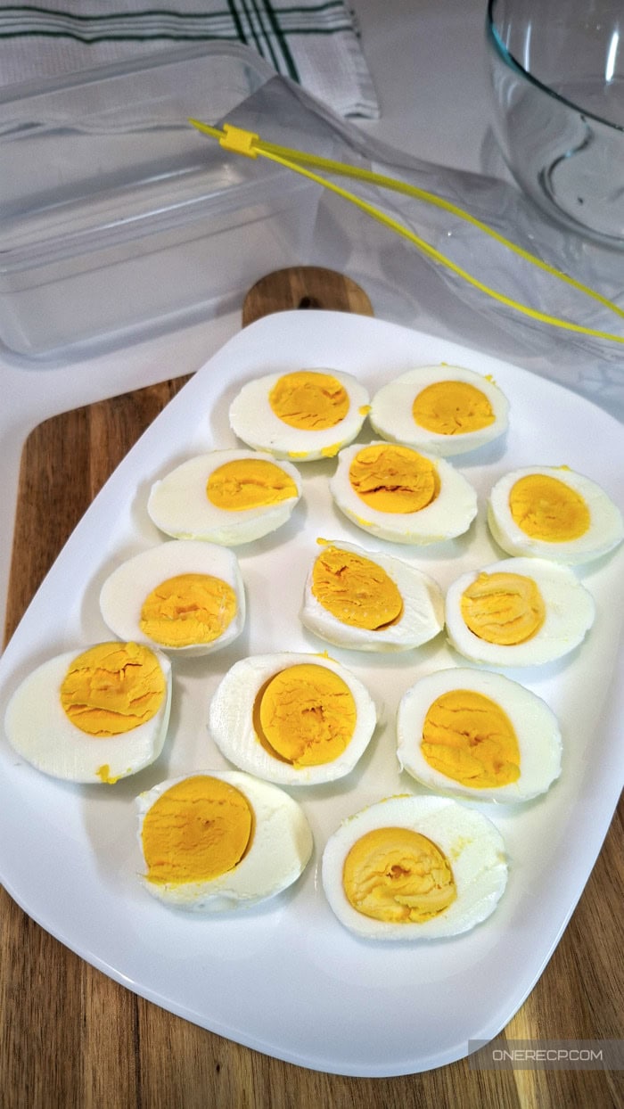 Hard-boiled eggs cut in half on a white plate before the yolks are separated from the whites.