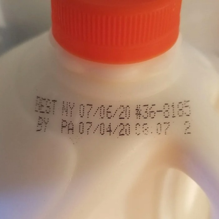 a close up of the sell by and best by dates on a bottle of unopened milk