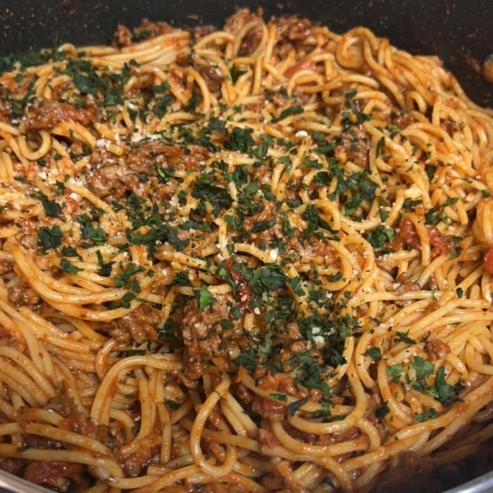 a close up of spaghetti pasta with beef and tomato sauce in a deep pan