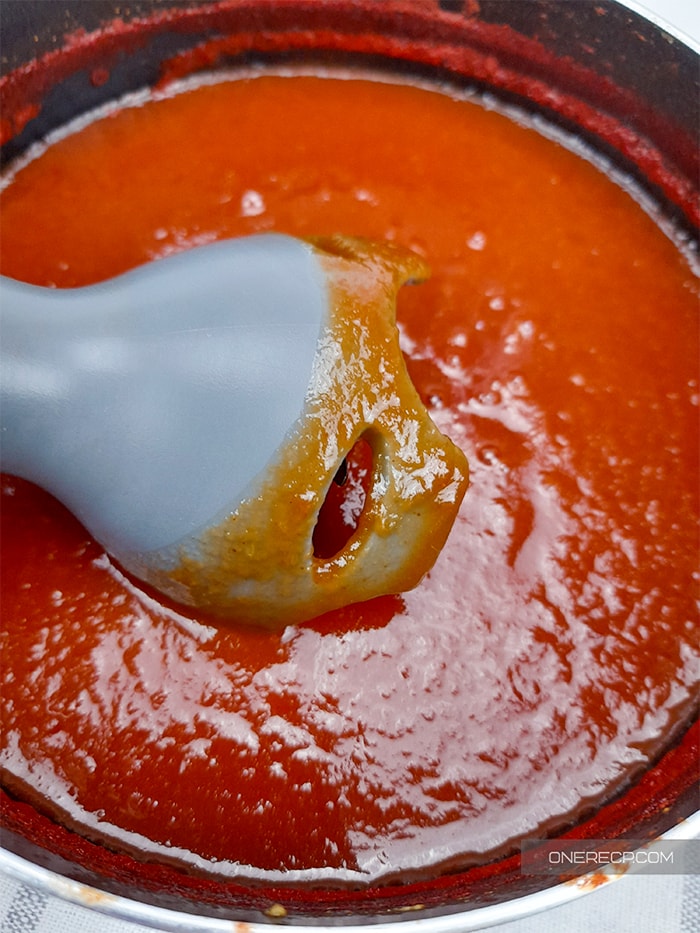 a bowl with smoothly blended BBQ sauce wihtout vinegar and the tip of the hand blender