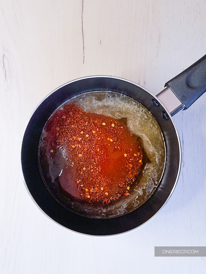 Combined ingredients for honey hot wing sauce in a small saucepan