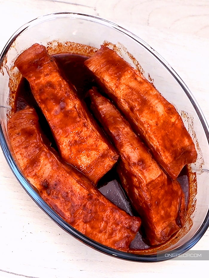 A glass bowl with marinated pork ribs