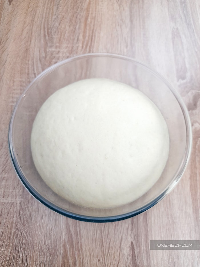 a glass bowl of smooth bun dough