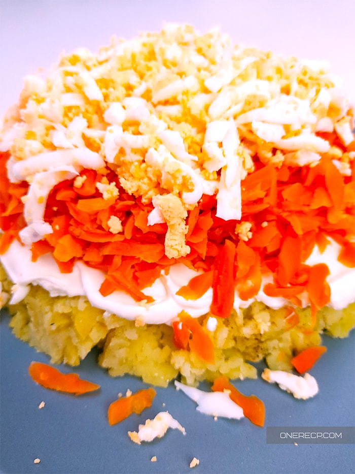 Savory salad cake made of layers of boiled potatoes, mayo, pickled carrots and boiled eggs