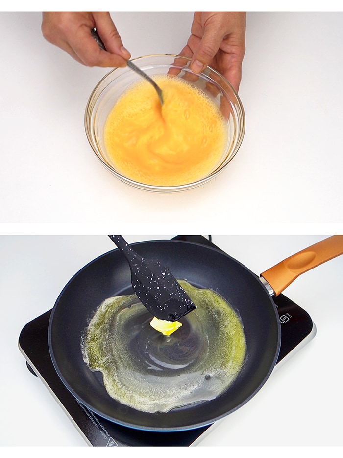 Whisking eggs in a glass bowl next to a skillet with melted butter