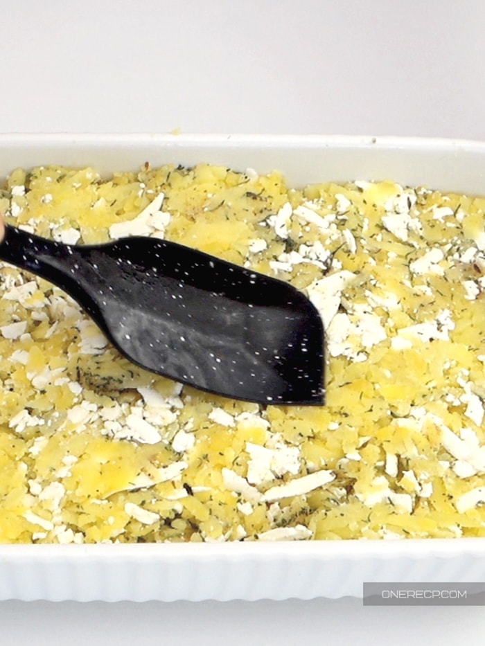 Smoothing shredded potato casserole with a spatula