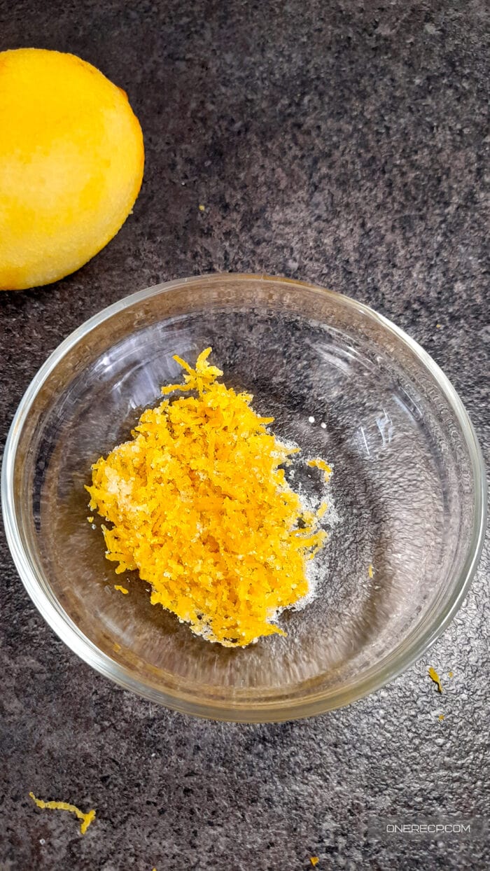 Lemon zest mixed with sugar in a glass bowl, ready to be used as a flavorful sweetener.
