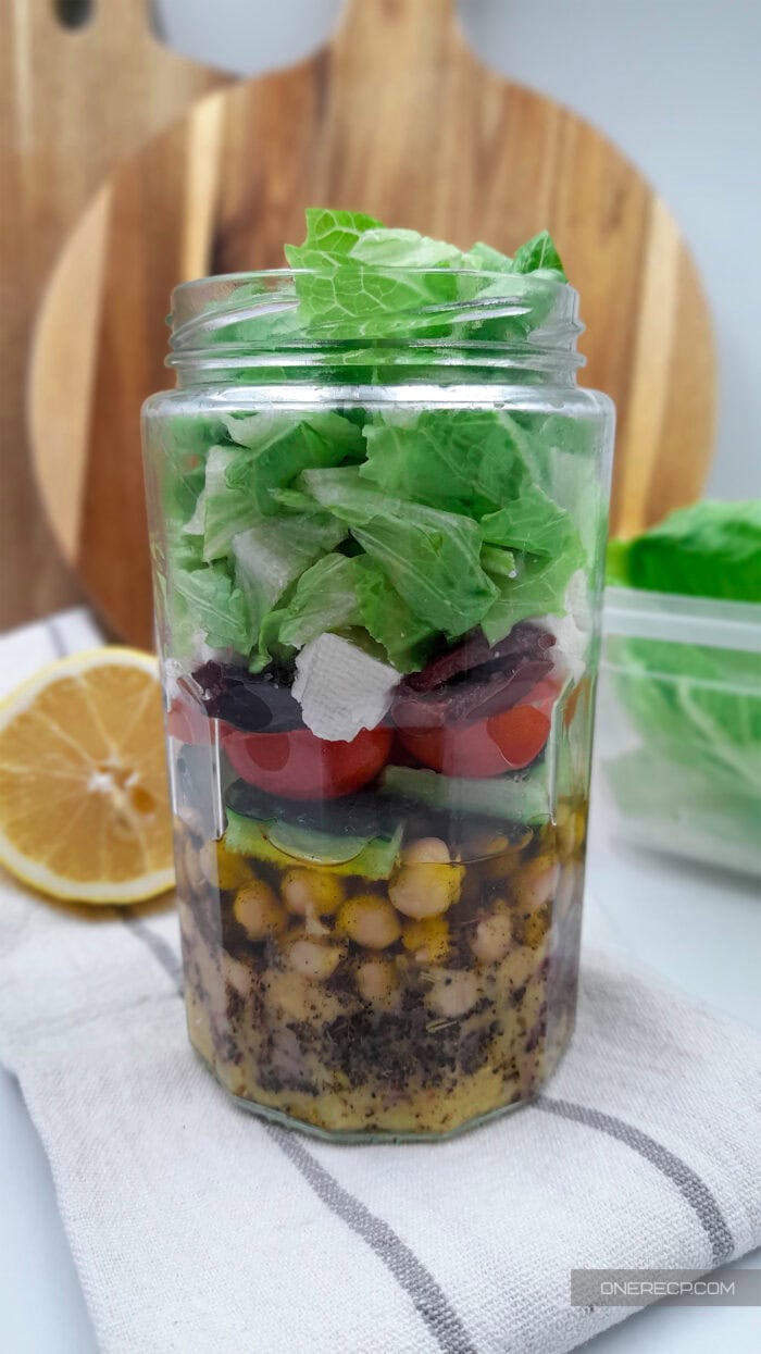 A layered mason-jar salad with lettuce on top and hearty ingredients below, showing a grab-and-go meal prep option that keeps lettuce crisp in the fridge.