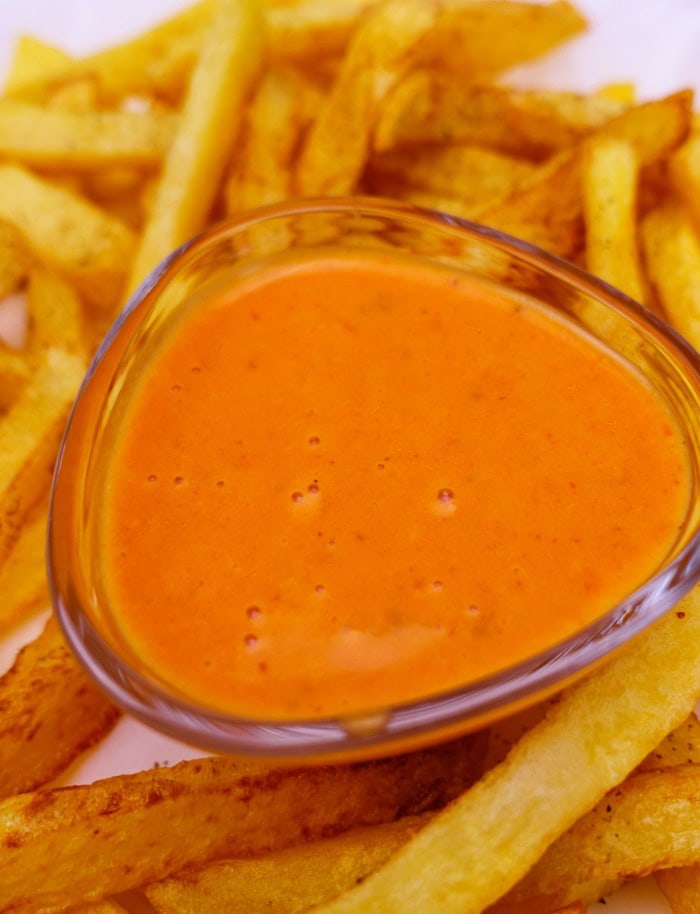 a small cup of mild buffalo wing sauce placed in fries