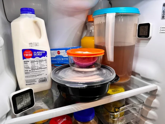 an opened fridge with a bottle of milk being stored deep in the back