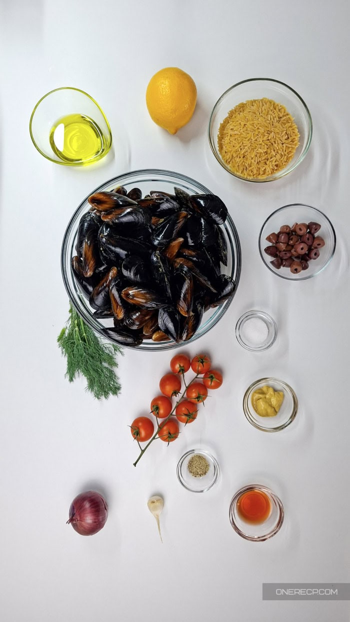 Ingredients for mussel and orzo salad with mustard-dill dressing arranged on a white surface