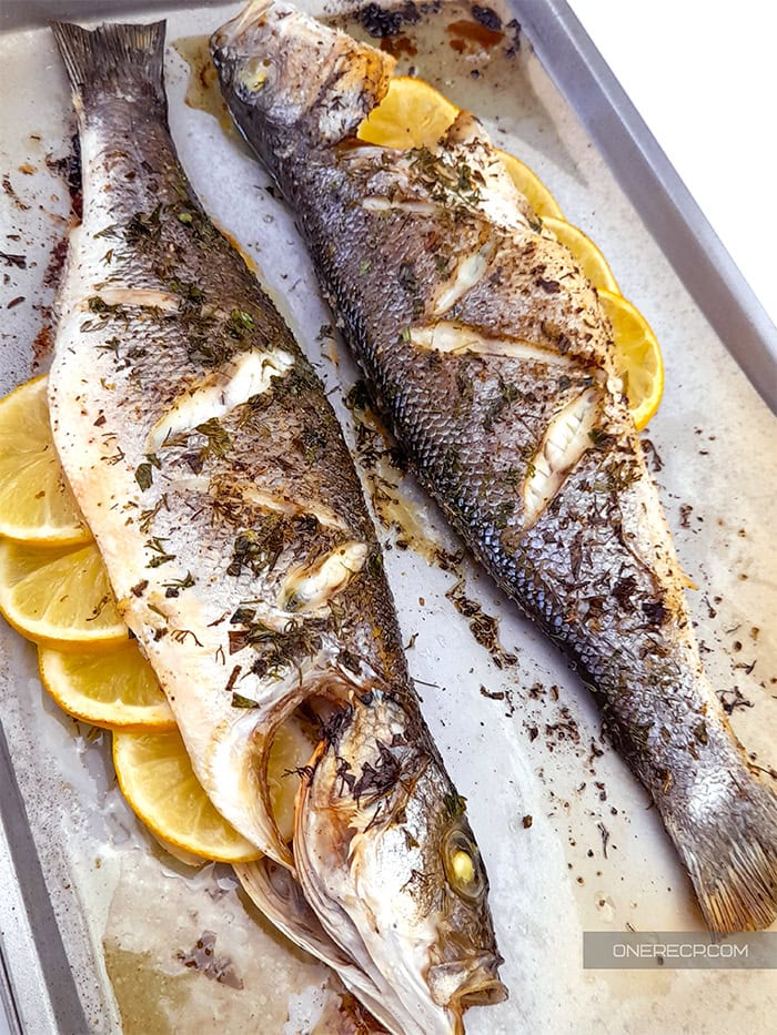 Two branzino fish oven roasted to golden brown on a baking sheet