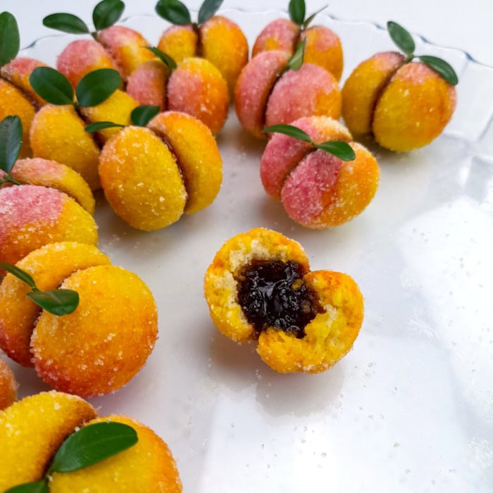 a batch of peach cookies with one showing the jam inside