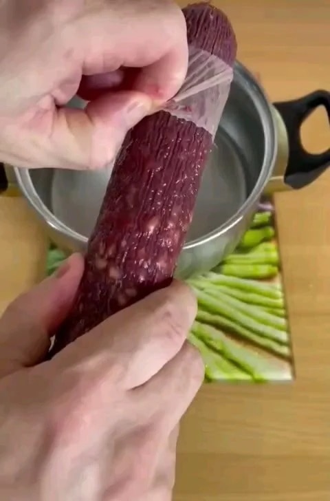 peeling off cellulose casing from salami