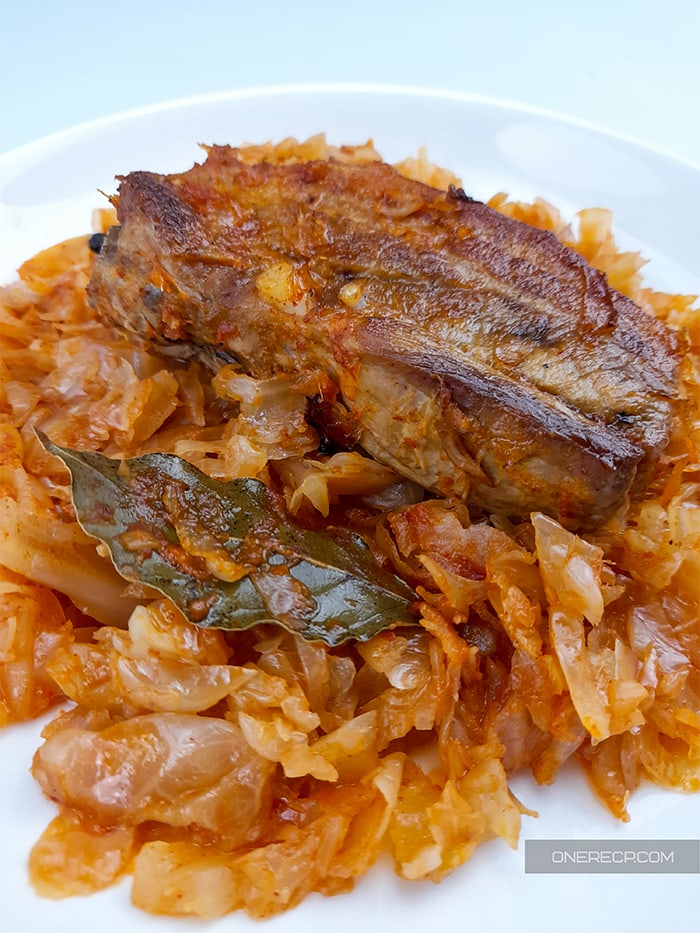 A plate with pork and sauerkraut seasoned with a bay leaf
