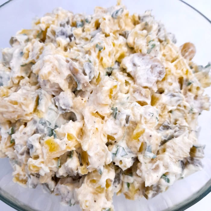 a large bowl with potato salad with mayonnaise, pickles, sterilized mushrooms, and parsley