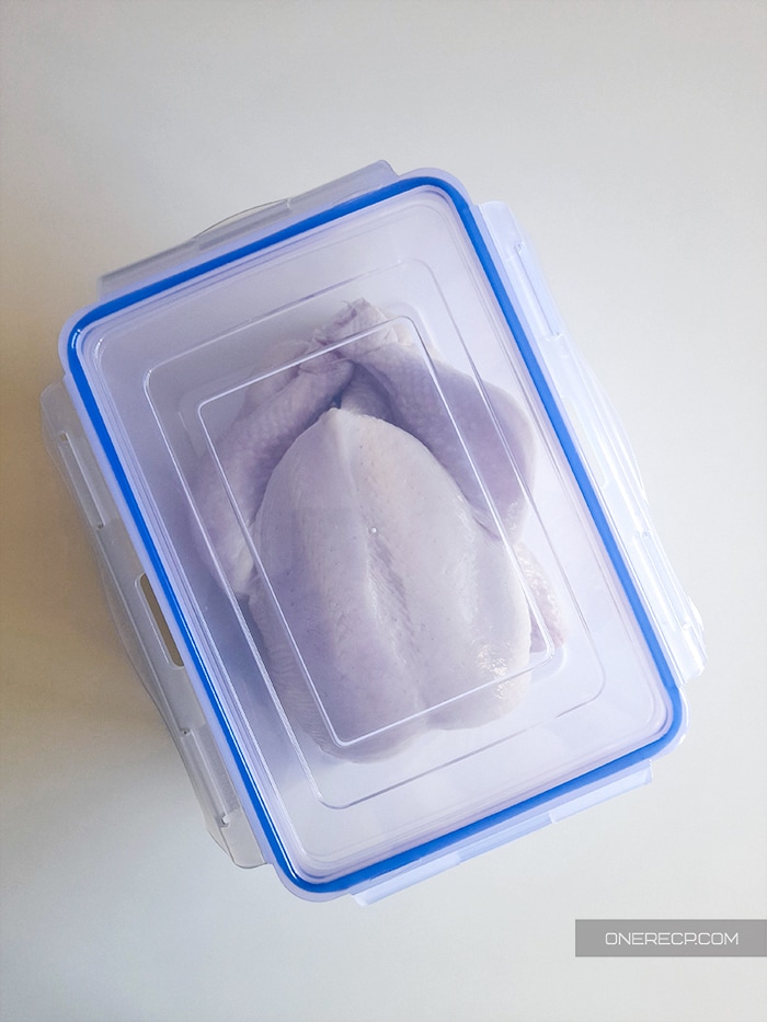 A raw chicken in an airtight plastic container
