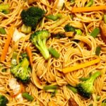 close-up view of chinese spring noodles with broccoli, carrots, and celery