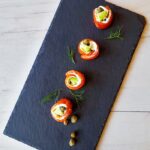 smoked salmon rolls with cream cheese, capers and dill on a black slate board