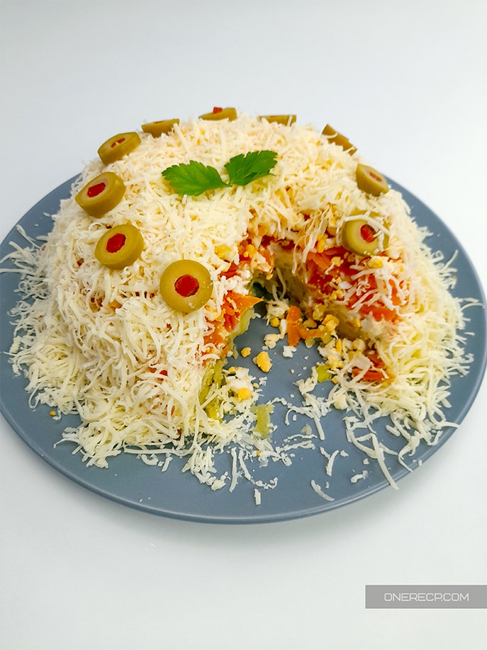 A plate of savory salad cake garnished with pickled olives and parsley