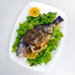 a plate with oven roasted sea bream over lettuce and lemons