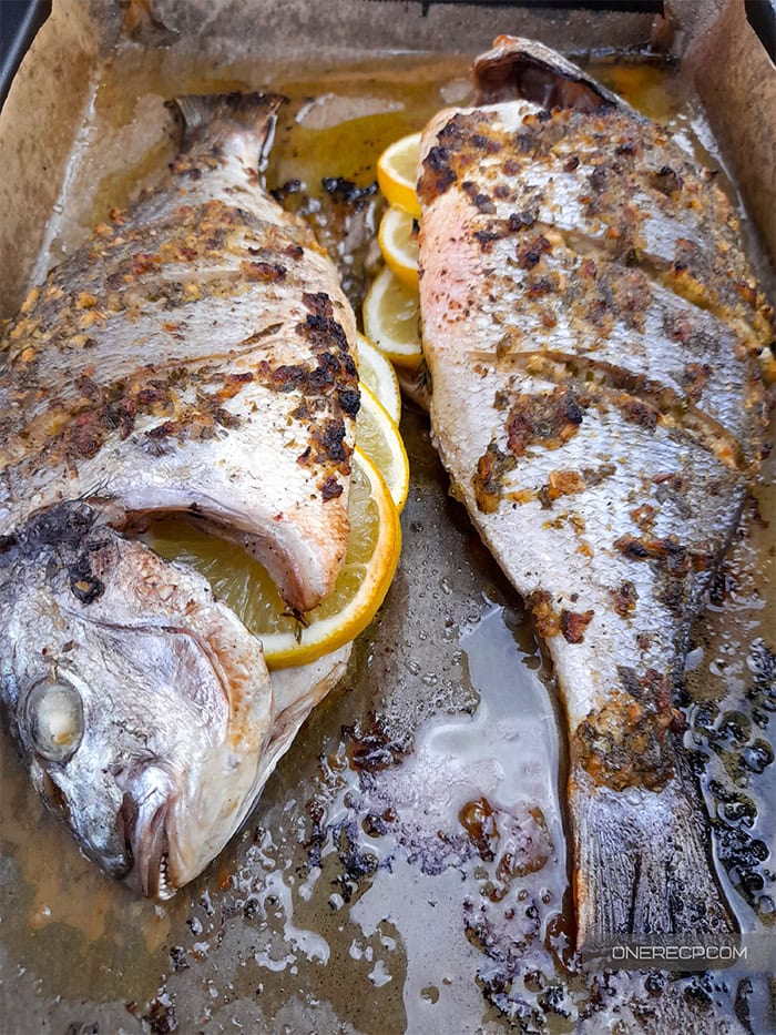 Two oven baked sea breams stuffed with sliced lemons