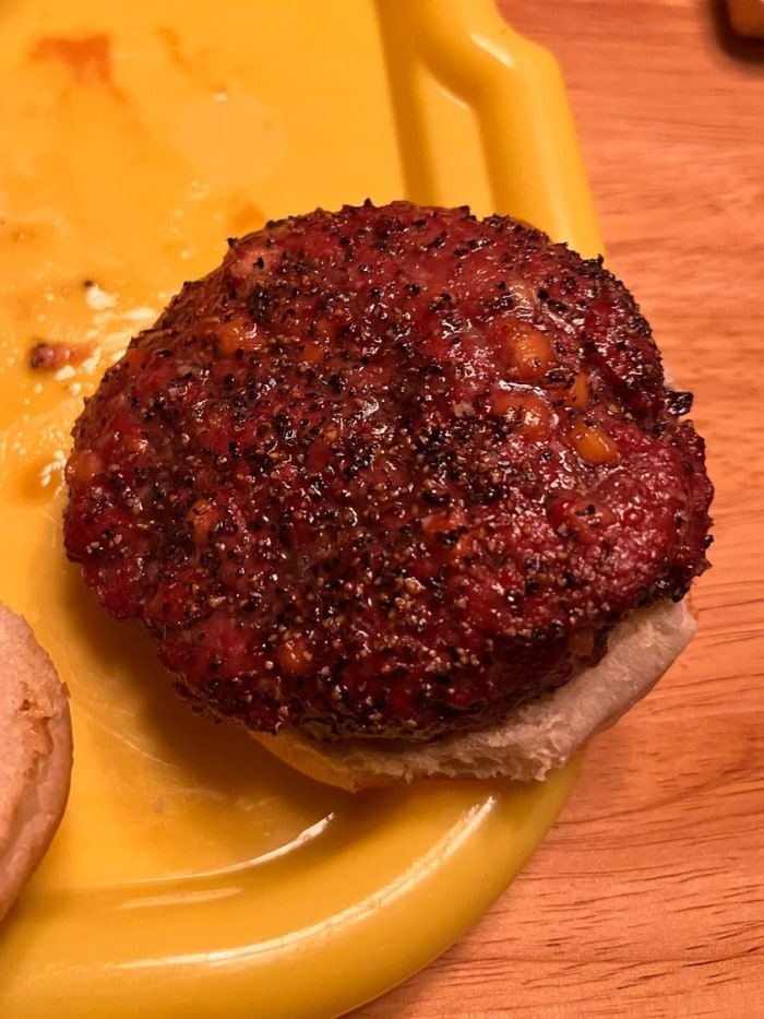 a close up of a burger cooked on a traeger that shows how much seasonig should be used