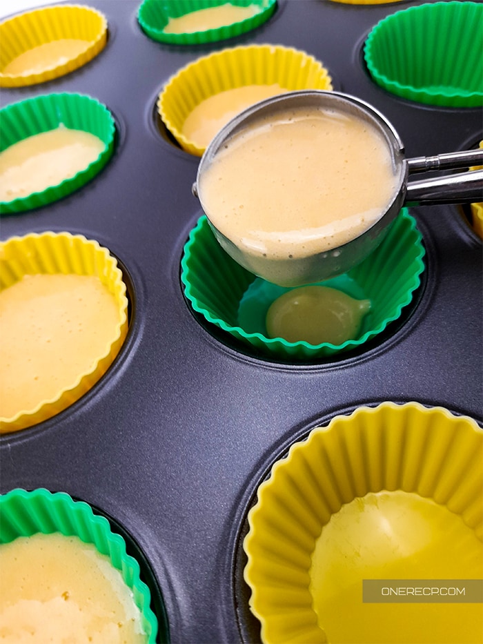 adding batter to silicone molds by using a scoop for better control 